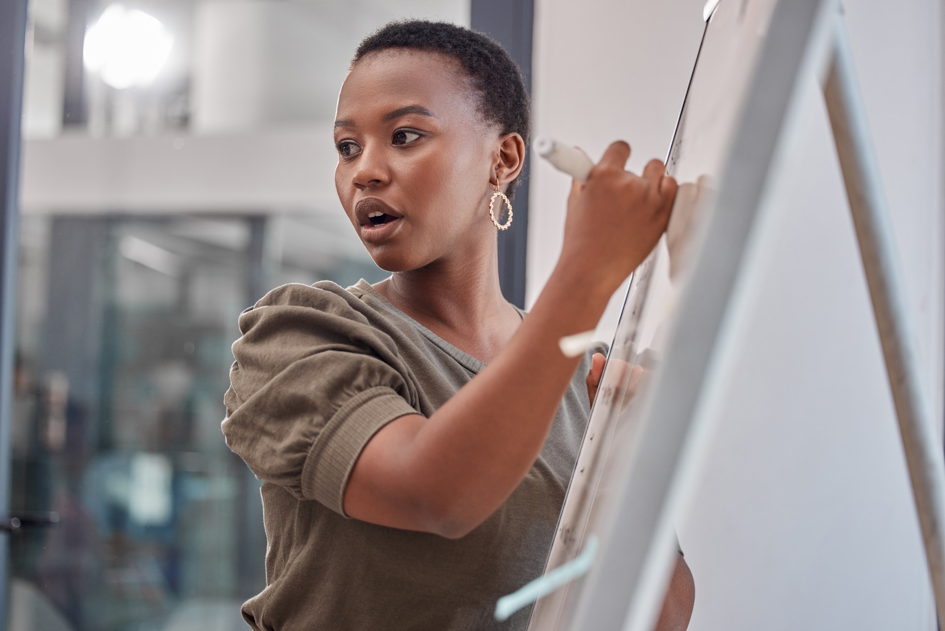 Shot of a young businesswoman writing on a board at the office